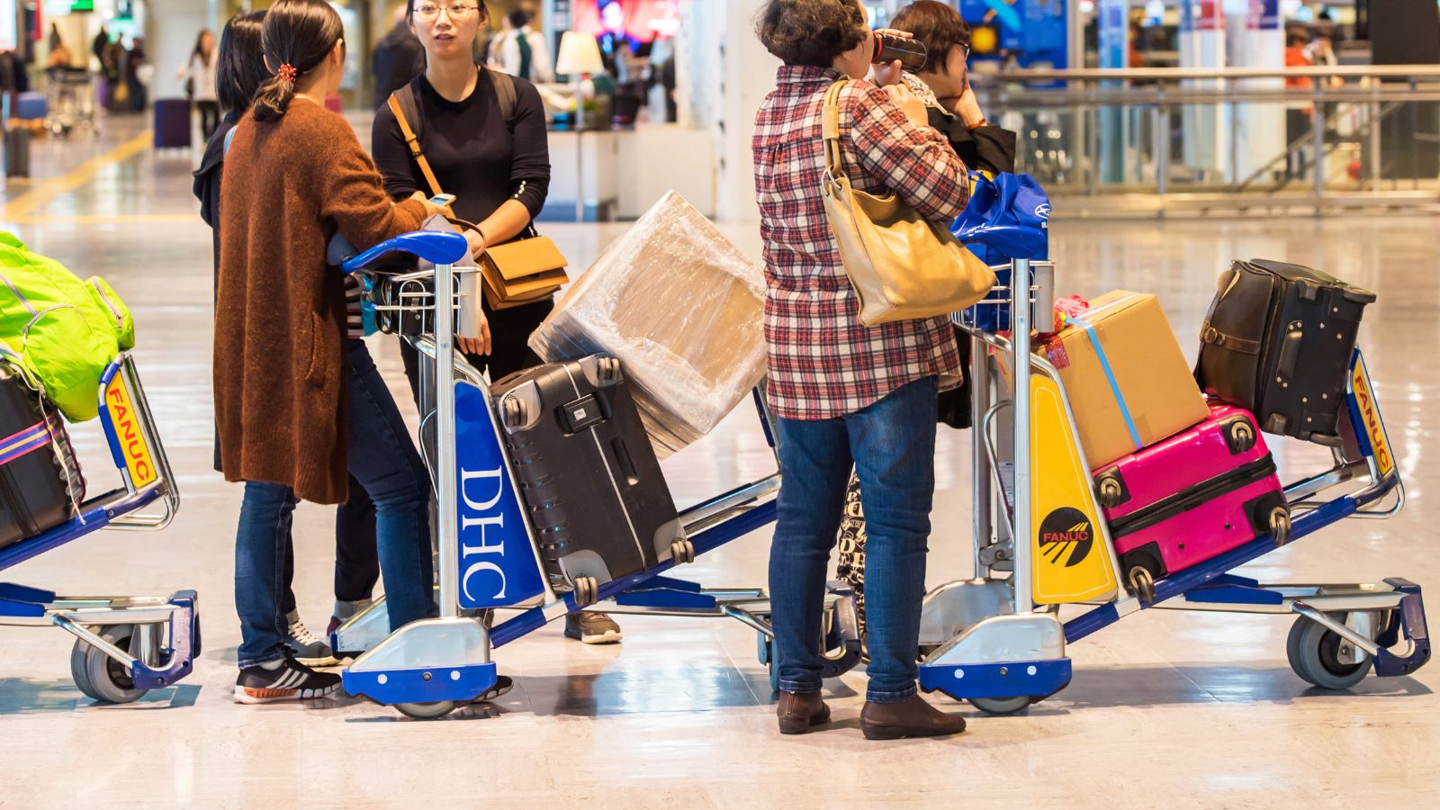A photo of passengers lining up at airport gate with luggages.