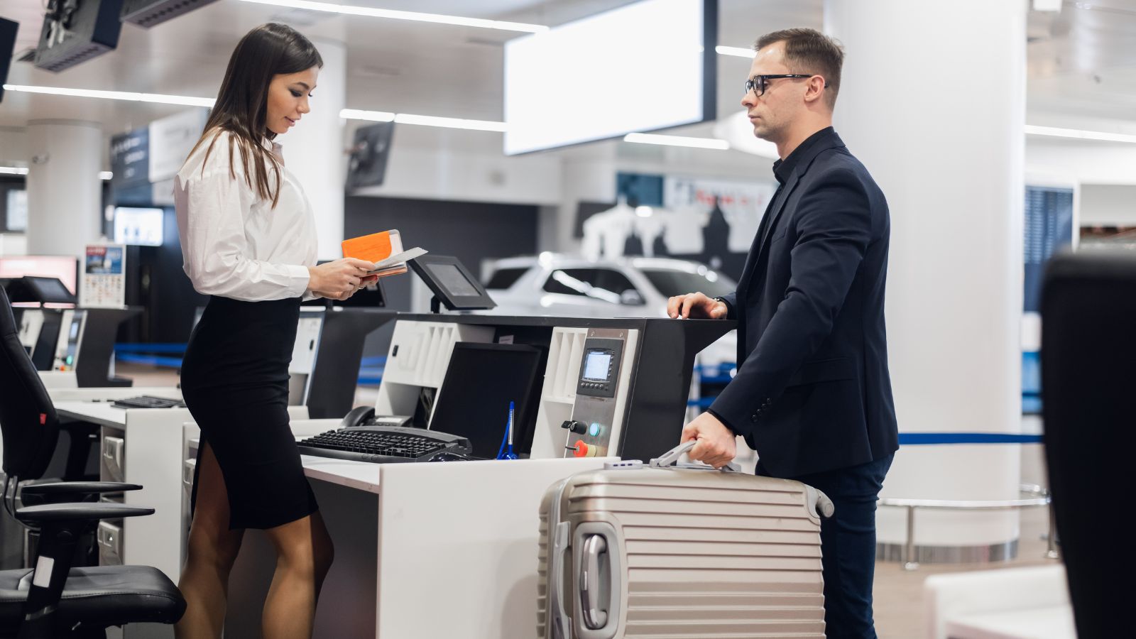 A photo of a traveler at an airport check-in counter paying extra baggage fee with suitcase beside them.