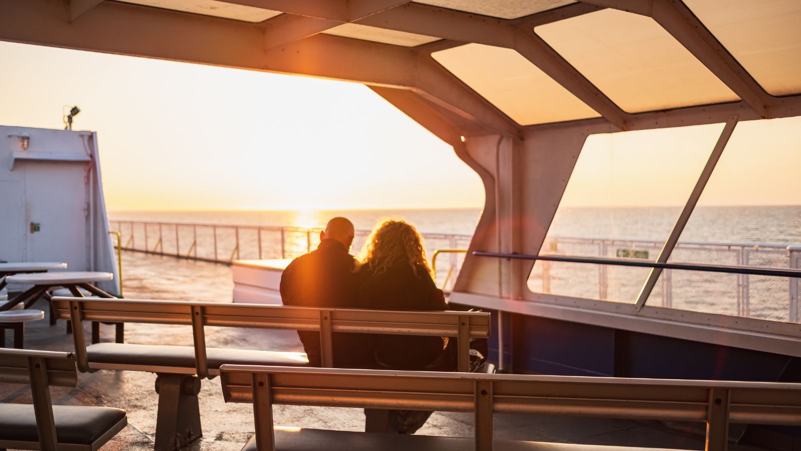 A photo of peaceful cruise ship deck at sunset few passengers walking open ocean background.