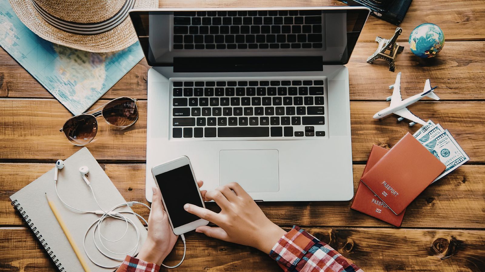 A photo of a traveler reviewing flight details and fees on a laptop with passport and boarding pass on the table.