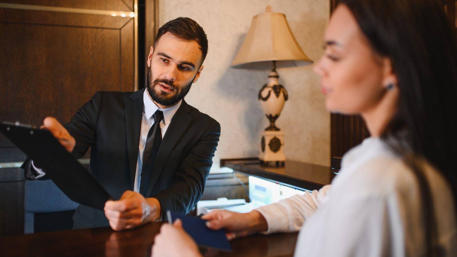 A photo of a hotel staff at a small reception desk warmly assisting a guest with personalized attention.