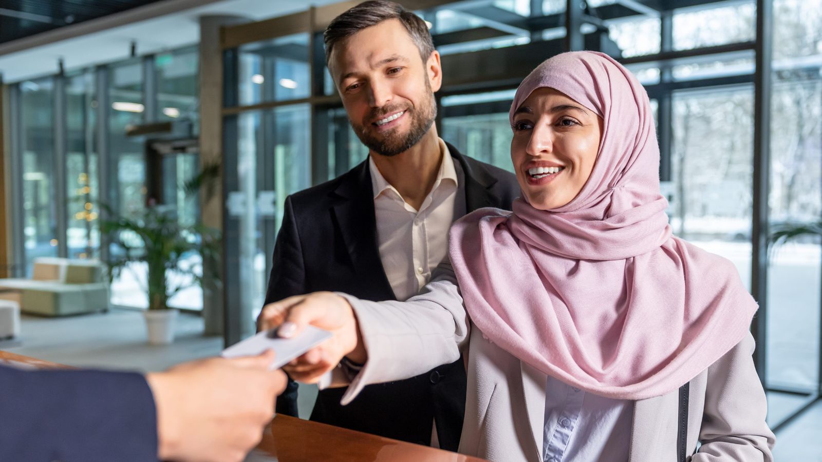 A photo of a hotel staff warmly greeting a guest at a small hotel reception desk, friendly and personal atmosphere.