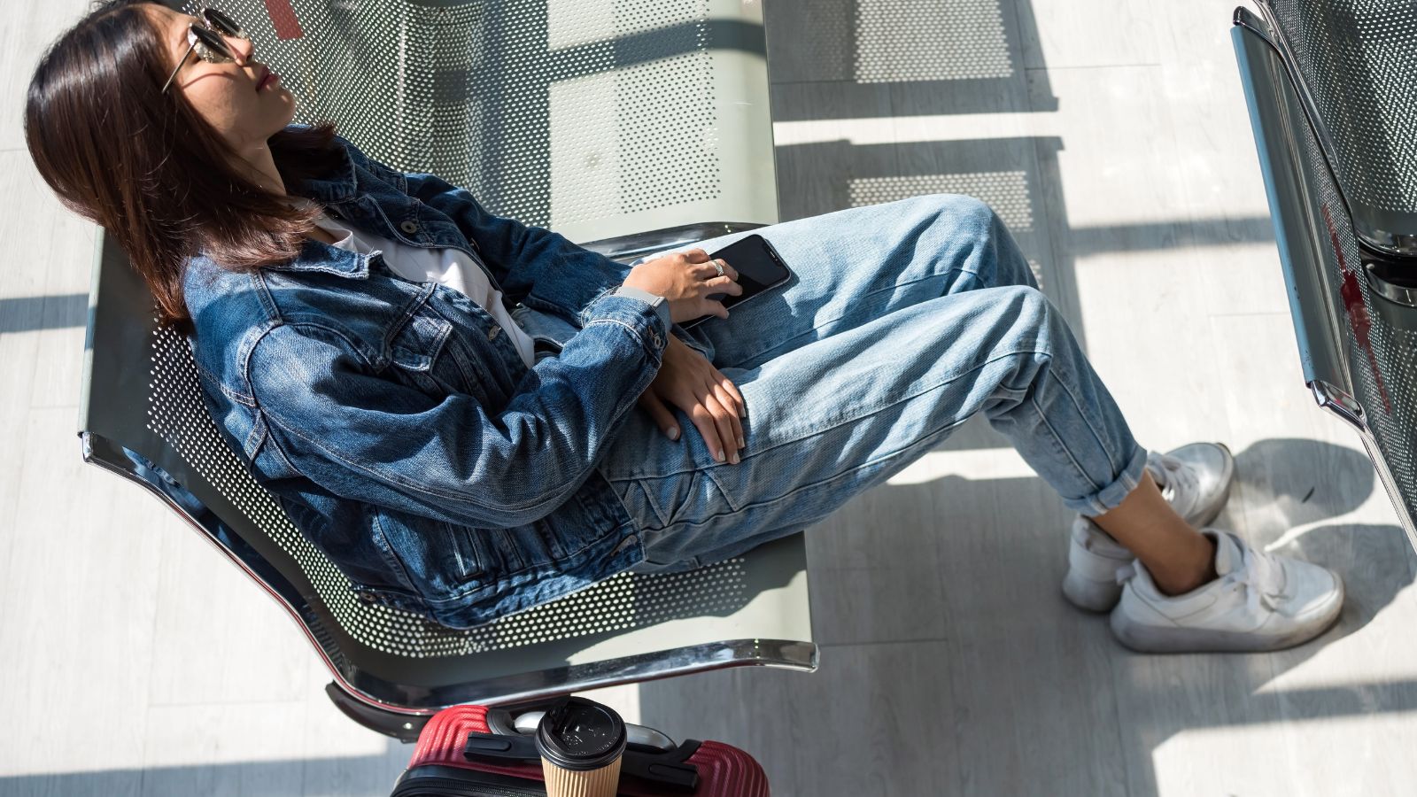 A photo of a traveler sitting at airport gate relaxed waiting comfortably no stress organized travel natural light candid.