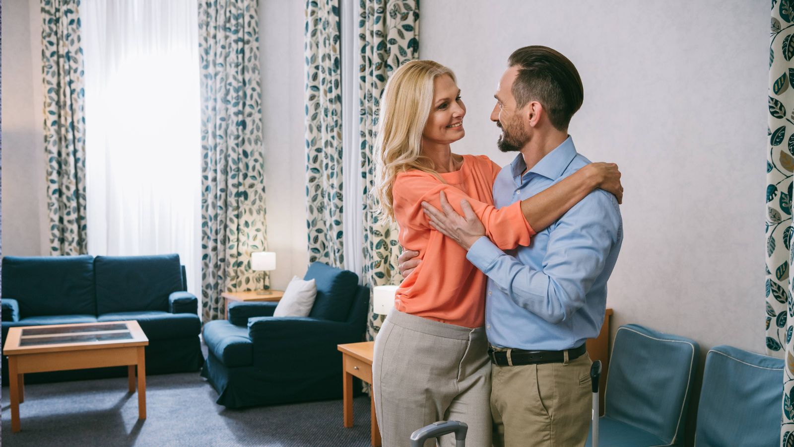 A photo of “mature romantic couple entering hotel room for first time warm welcoming interior comfortable space travel arrival moment natural light candid.