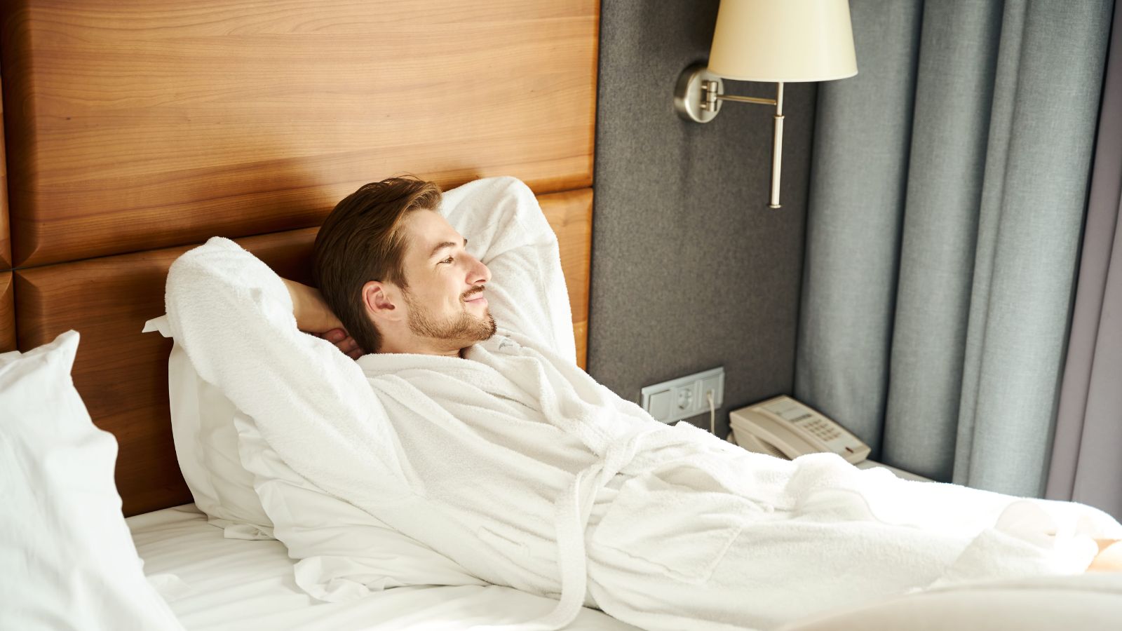 A photo of a raveler entering hotel room early placing luggage on bed looking relieved relaxed smooth check in experience natural light candid.