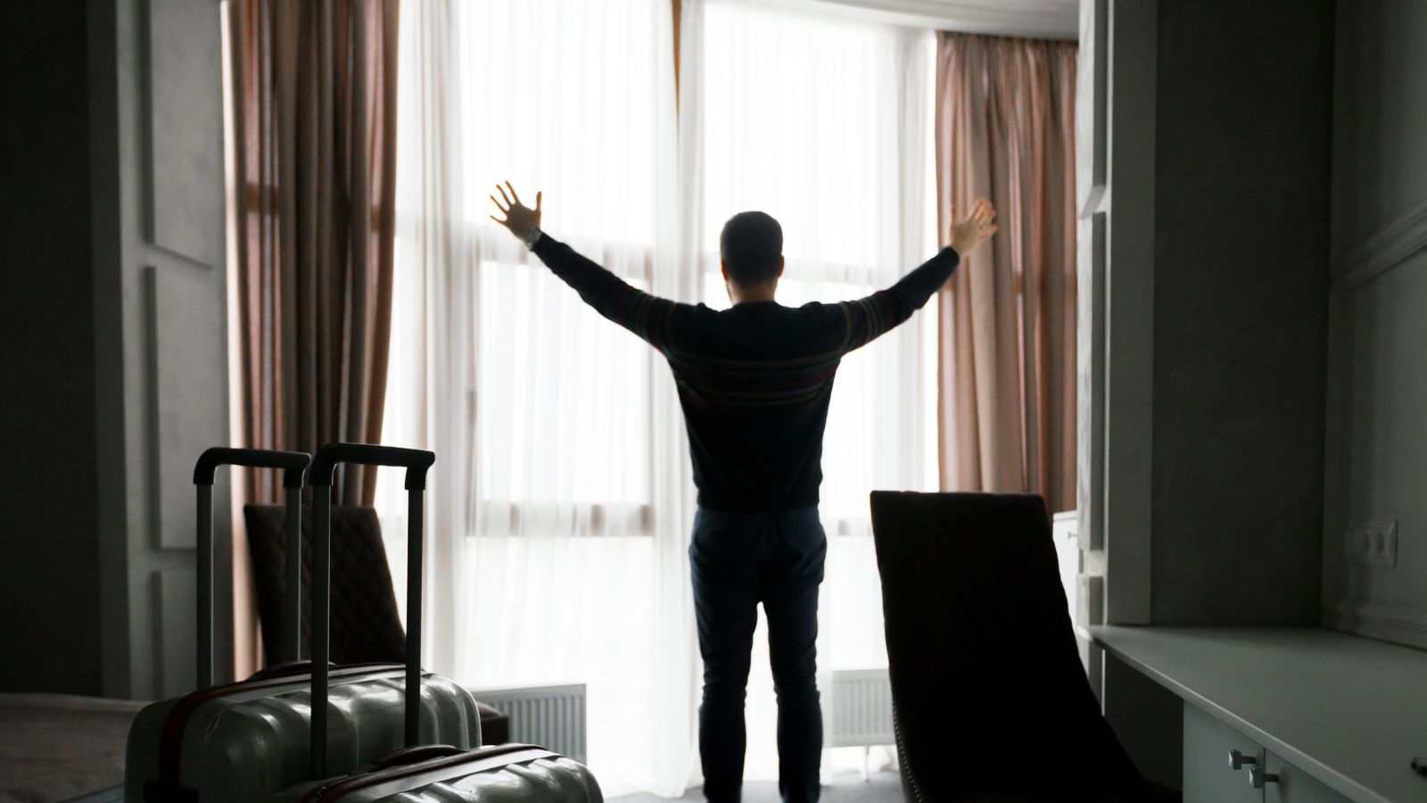 A photo of a traveler relaxing in hotel room after arrival comfortable settling in calm refreshed travel moment natural light.