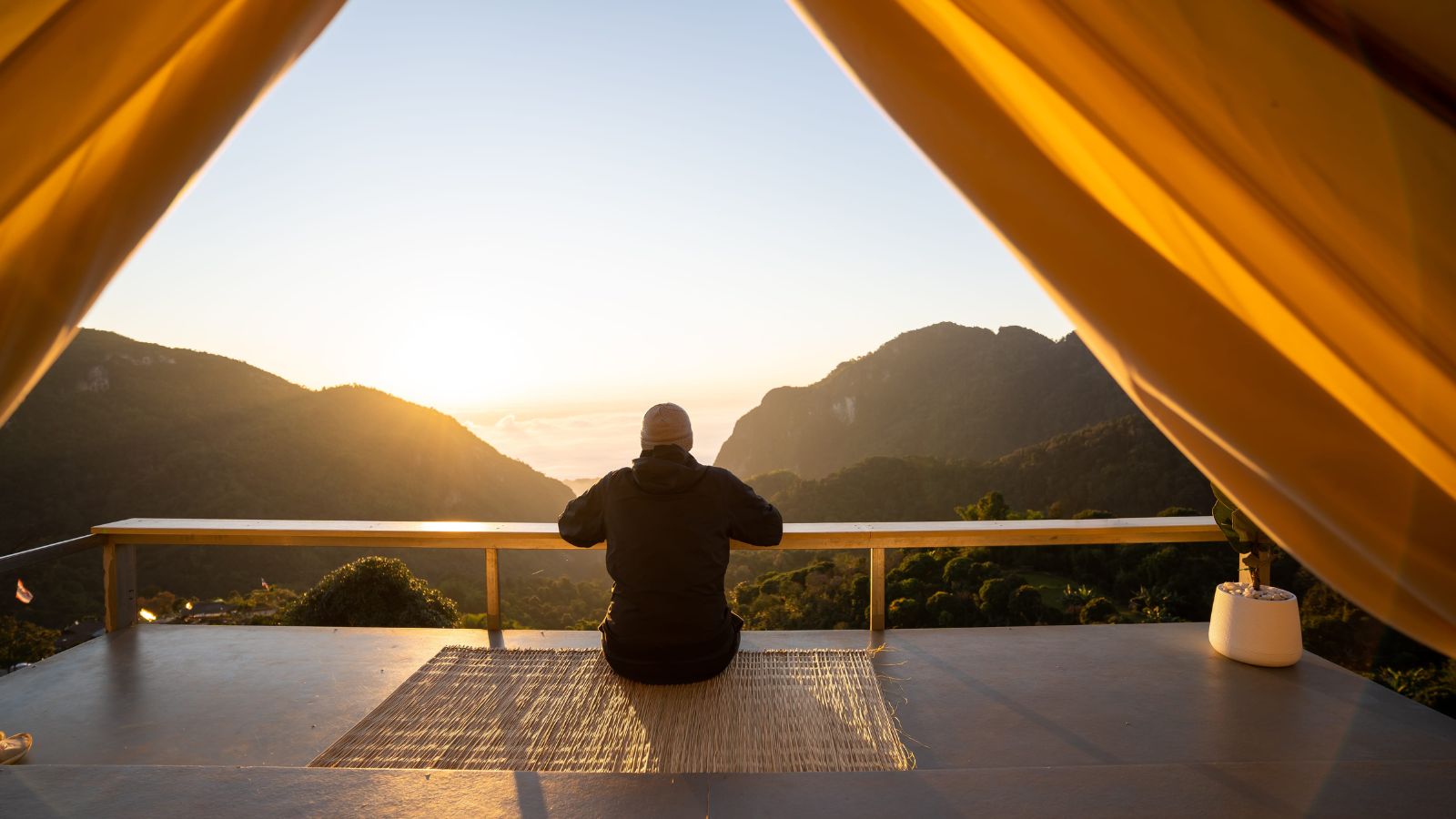 A photo of a relaxed traveler sitting at scenic viewpoint or cafe enjoying moment slow travel lifestyle peaceful natural light.