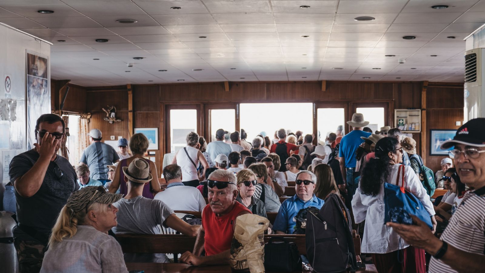 A photo of crowded cruise ship elevator lobby in morning with passengers waiting for shore excursion.