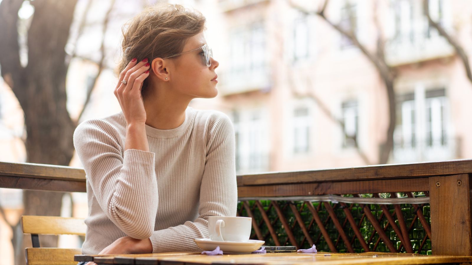 A photo of a traveler sitting peacefully at an outdoor café watching the city life during sunset, relaxed and unhurried.
