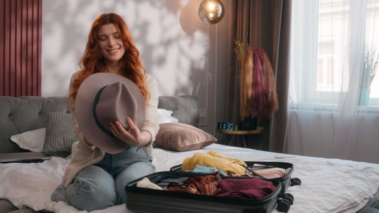 A photo that shows a woman sitting at her bed, facing luggage.