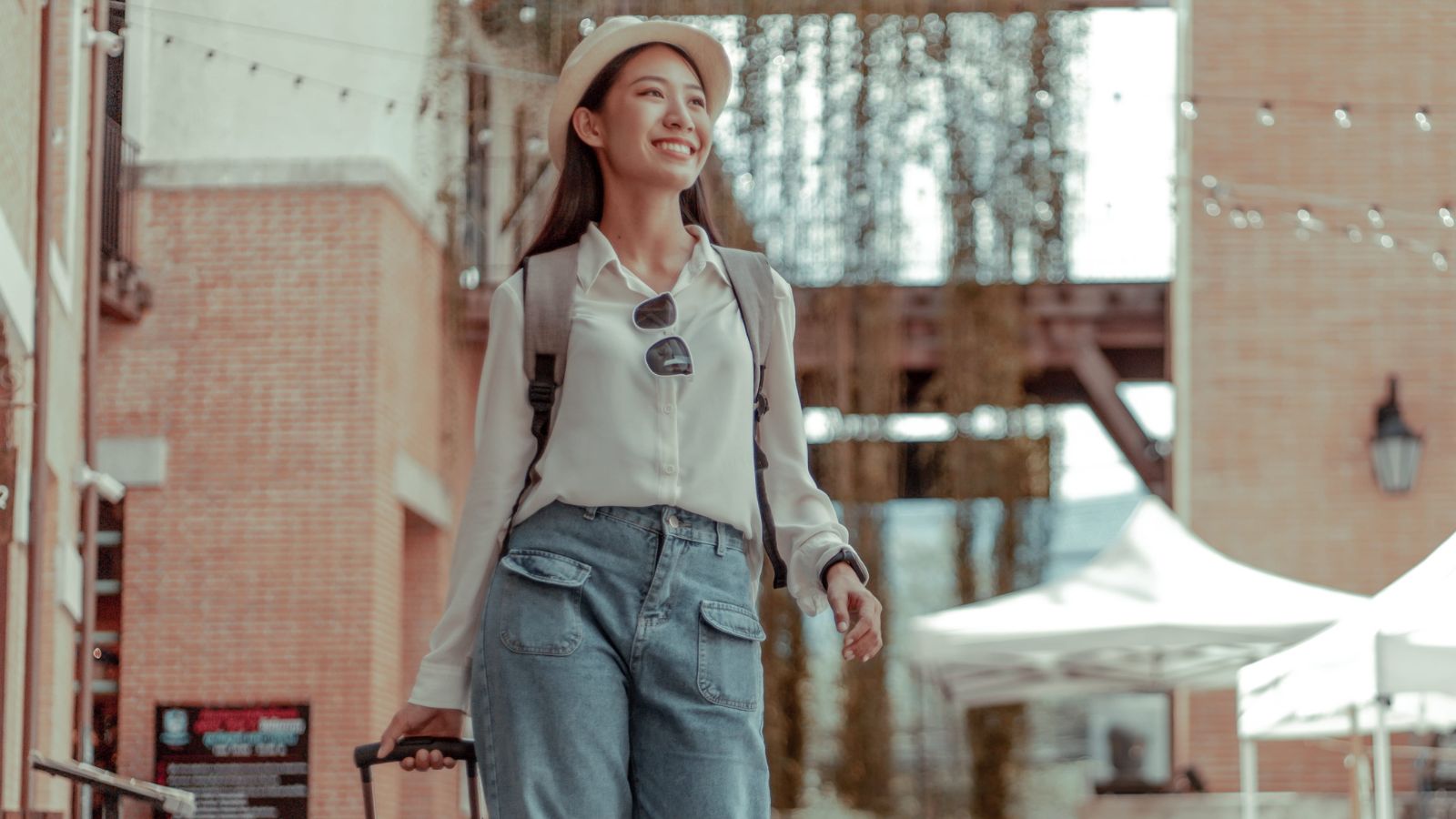 A photo of a traveler walking through a Canadian city street with a small suitcase and backpack relaxed travel light concept.