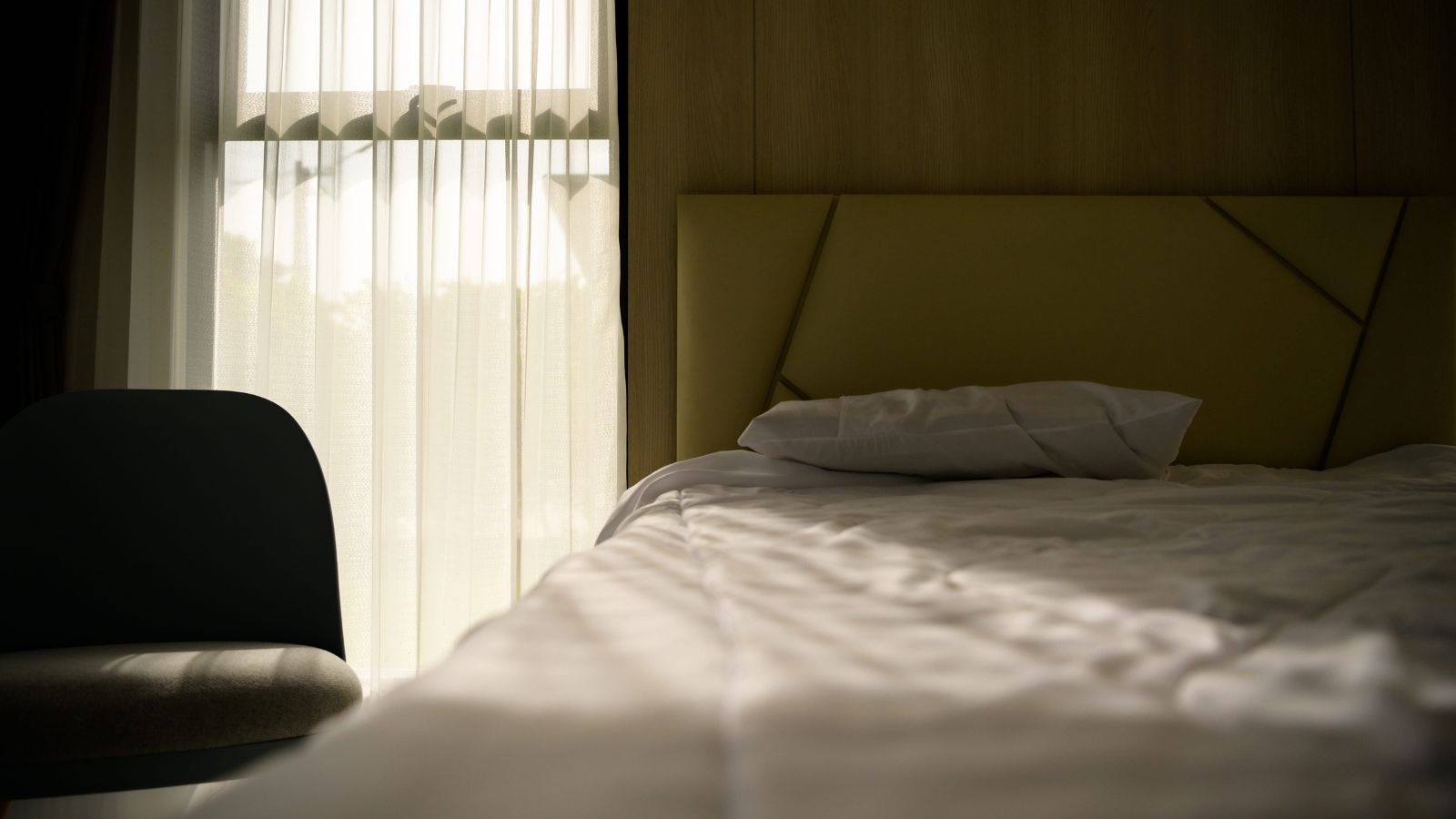 A photo that shows quiet hotel room interior soft lighting comfortable bed peaceful atmosphere minimal noise restful travel stay.