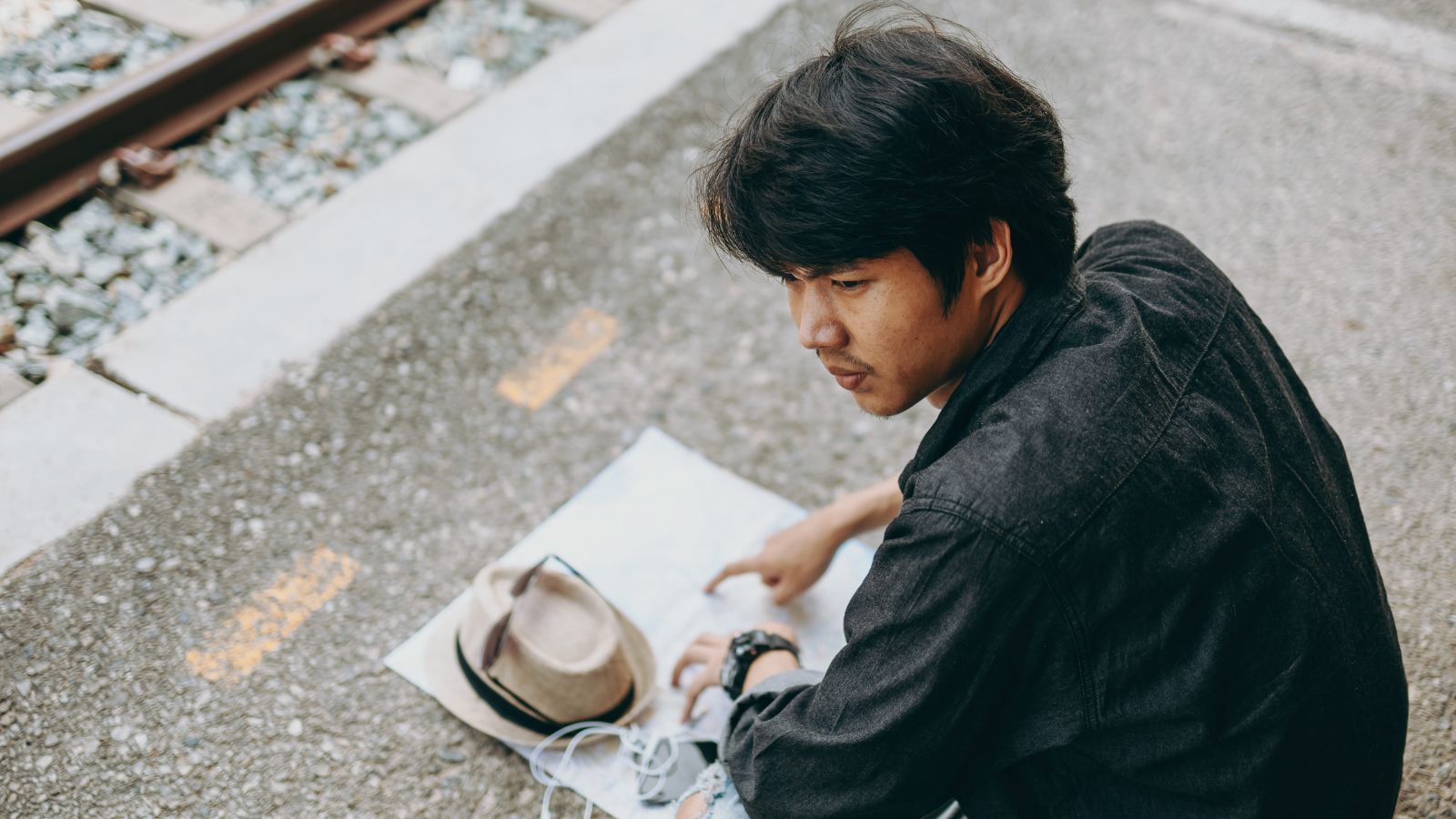 A photo of a man sitting at the street.