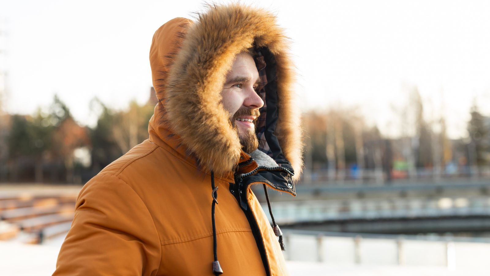 A photo of a traveler wearing a thick winter coat looking uncomfortable on a mild day in a Canadian city.