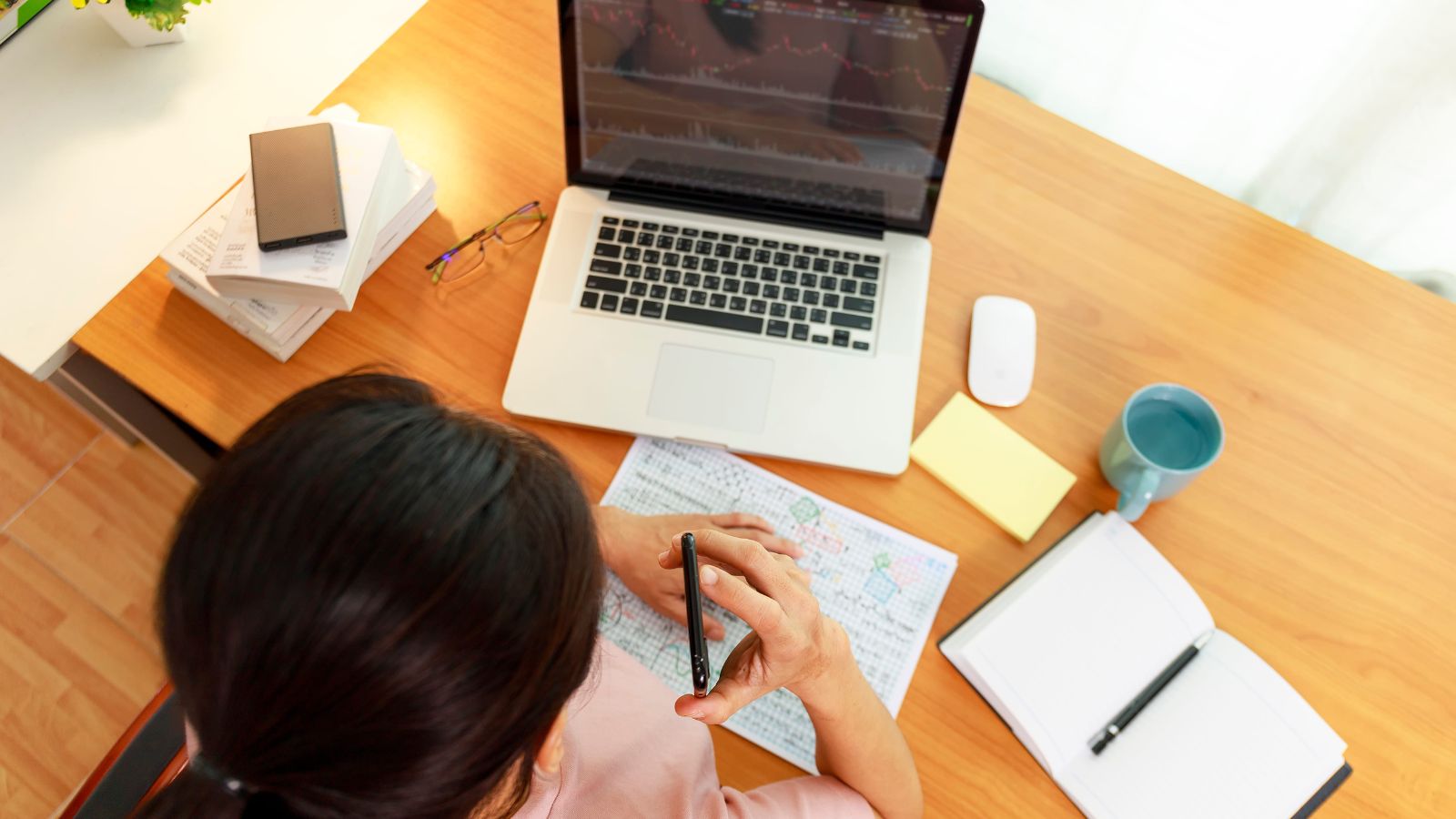 A photo of a traveler planning a trip with a laptop, city map, and a notebook filled with a packed hourly travel schedule.