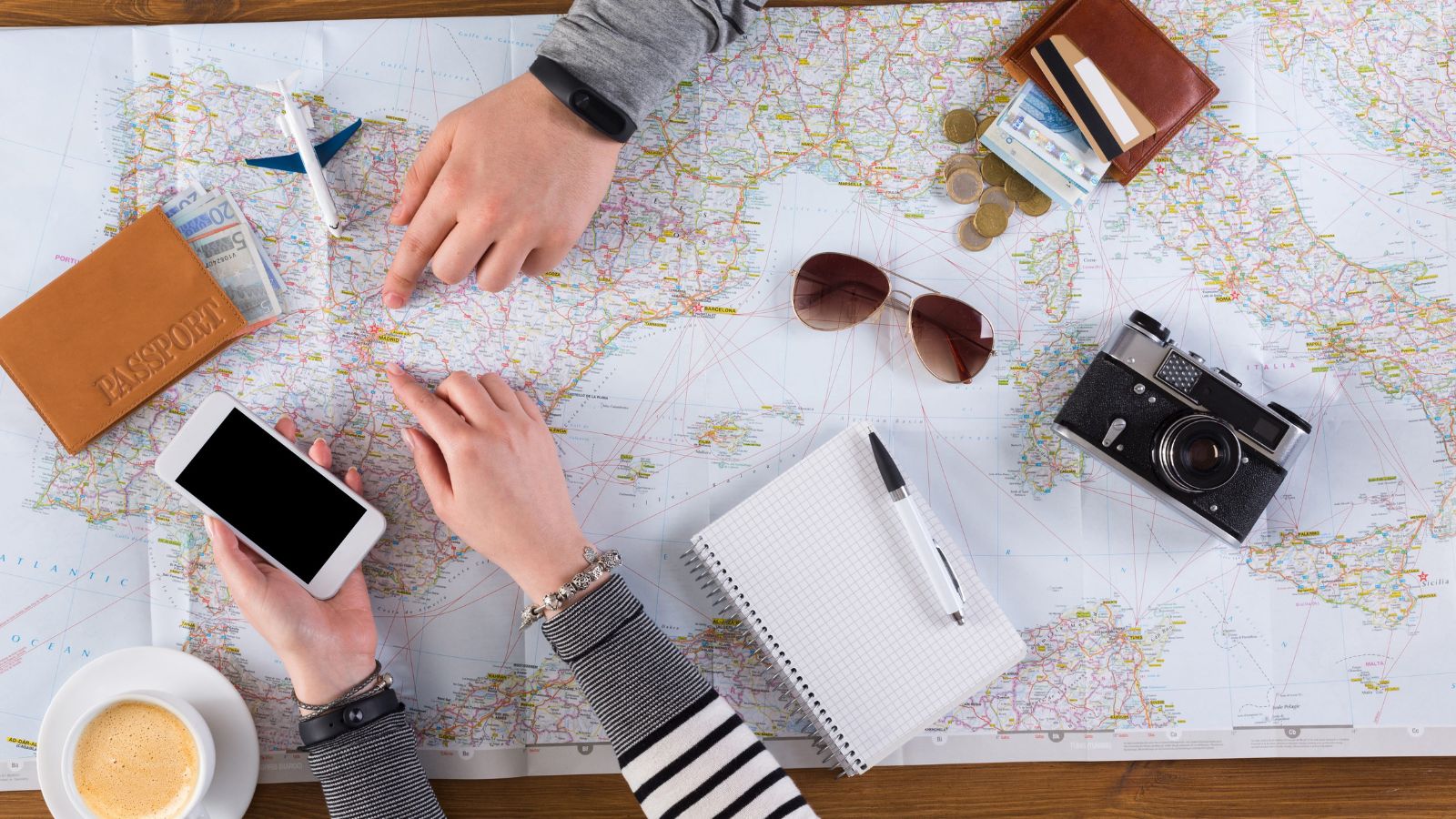 A photo of a romantic couple planning itinerary with map notebook and phone considering schedule travel planning calm indoor setting natural light.