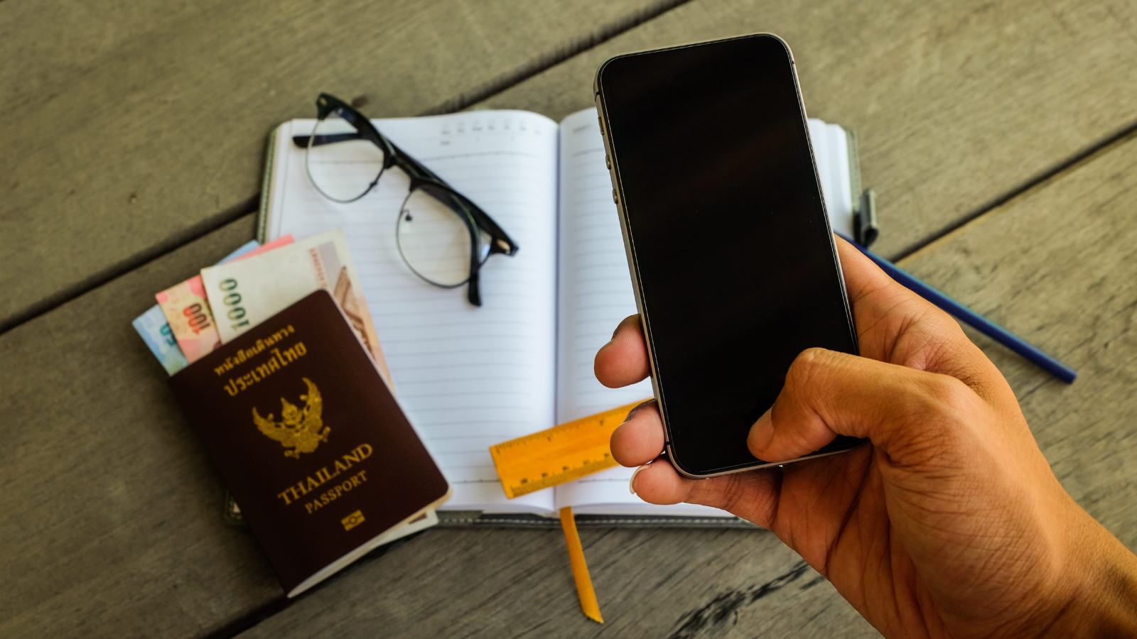 A photo that shows a traveler reviewing travel itinerary notebook map and phone organized trip planning calm setup natural light flat lay.
