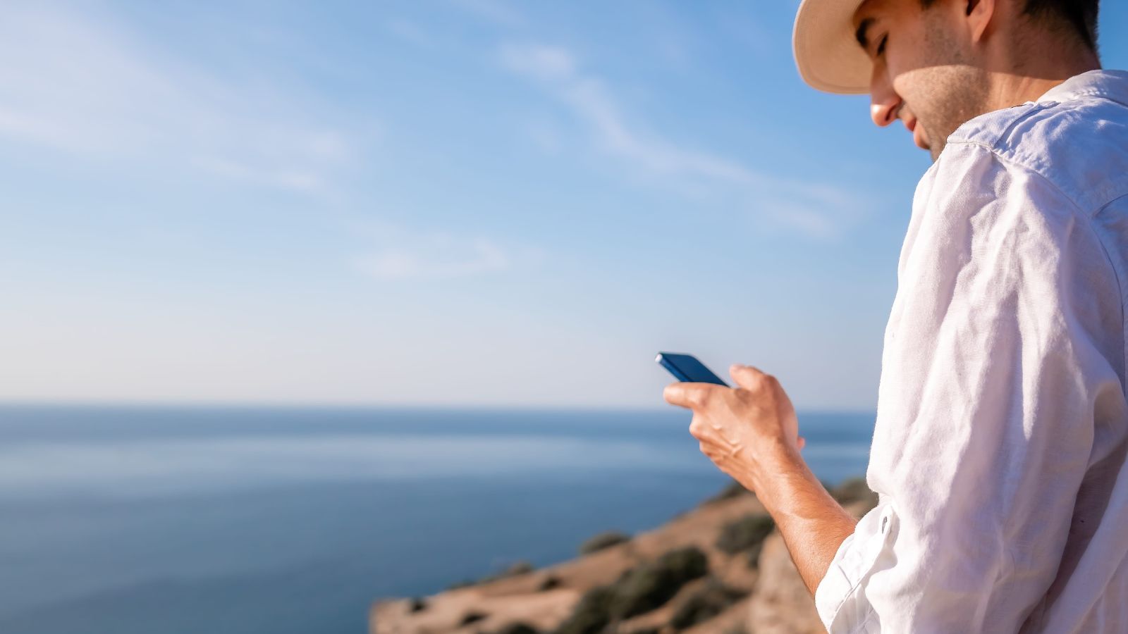 A photo of traveler sitting at scenic vacation spot looking thoughtful slightly distracted checking phone or planner peaceful outdoor setting natural light.