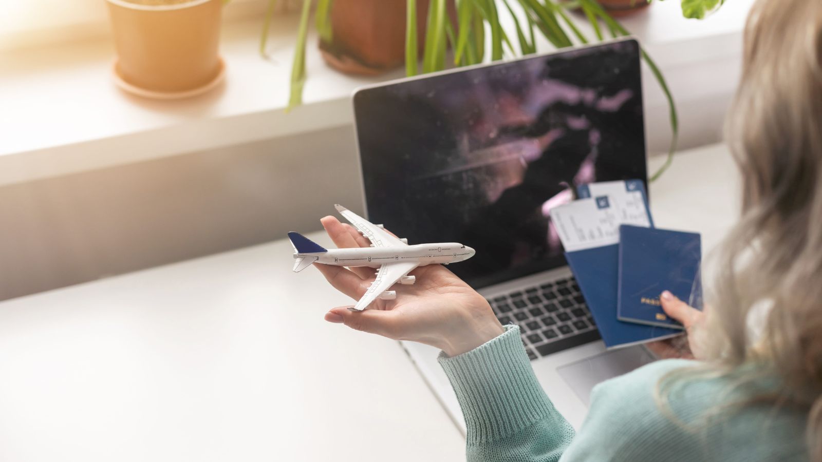 A photo of a traveler booking a flight on a laptop with passport and credit card on the table, travel planning scene.