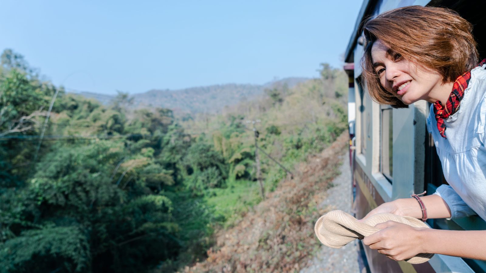 A photo of a traveler sitting by a large train window watching the changing European landscape during a comfortable train ride.