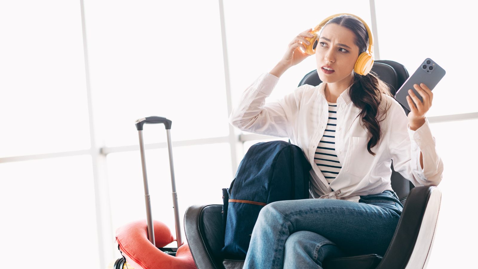 A photo of a woman, sitting beside her luggage, looks so stressed.