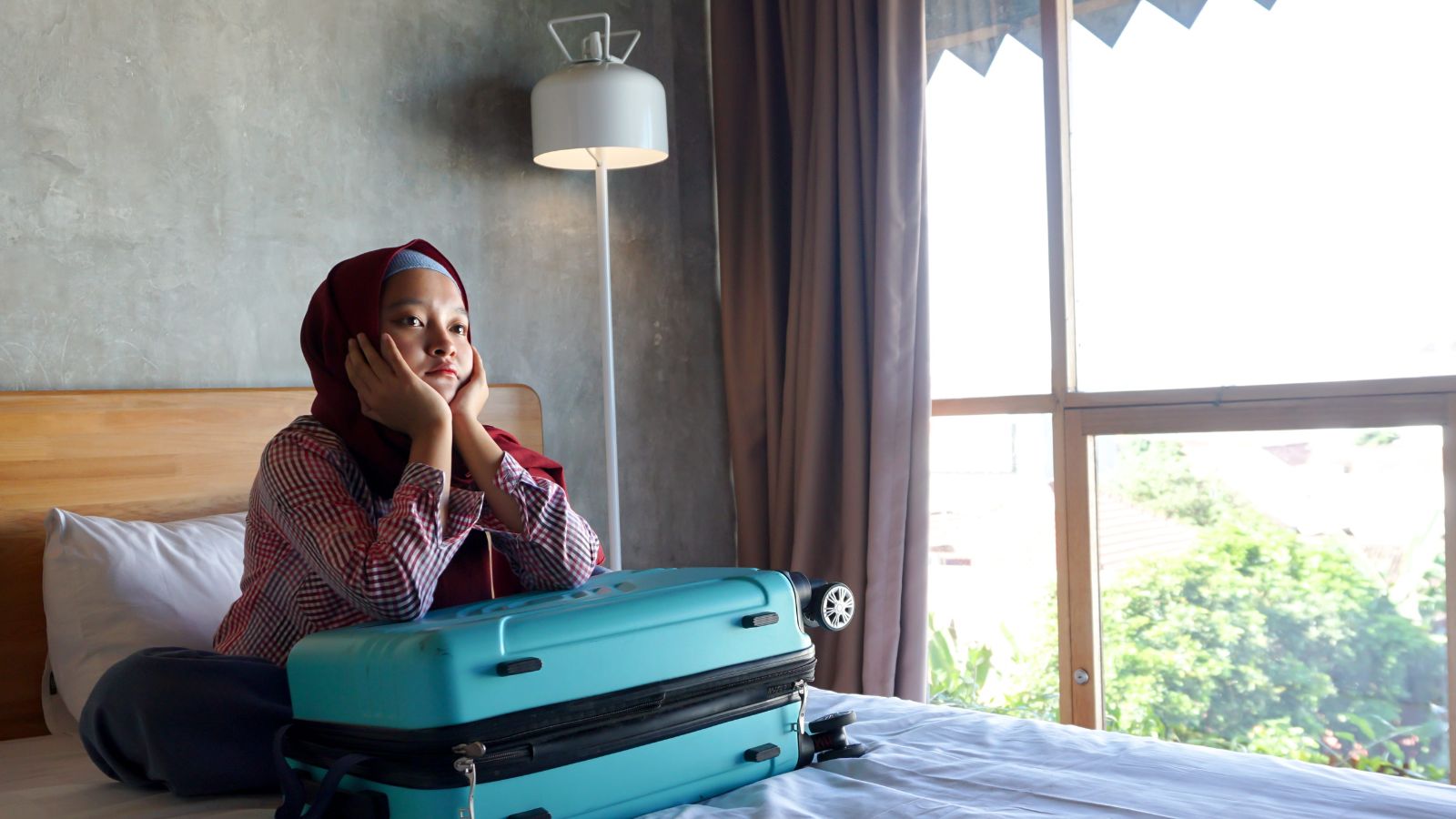 A photo of a traveler in high floor hotel room with view looking slightly annoyed reacting to noise or inconvenience realistic travel moment.