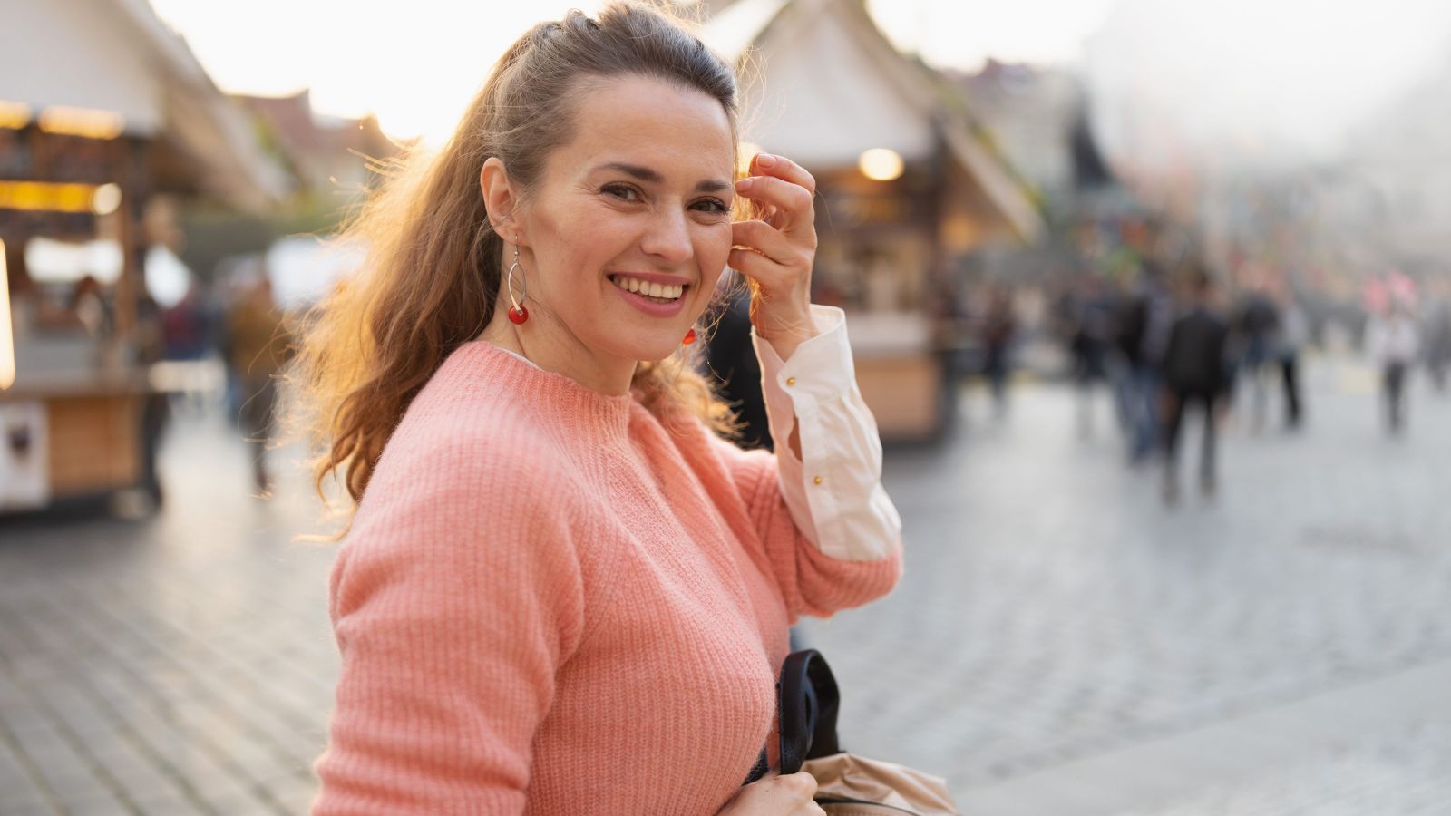 A photo of a solo traveler strolling along vibrant city street enjoying nearby cafés shops and attractions happy relaxed travel experience daylight natural light candid.