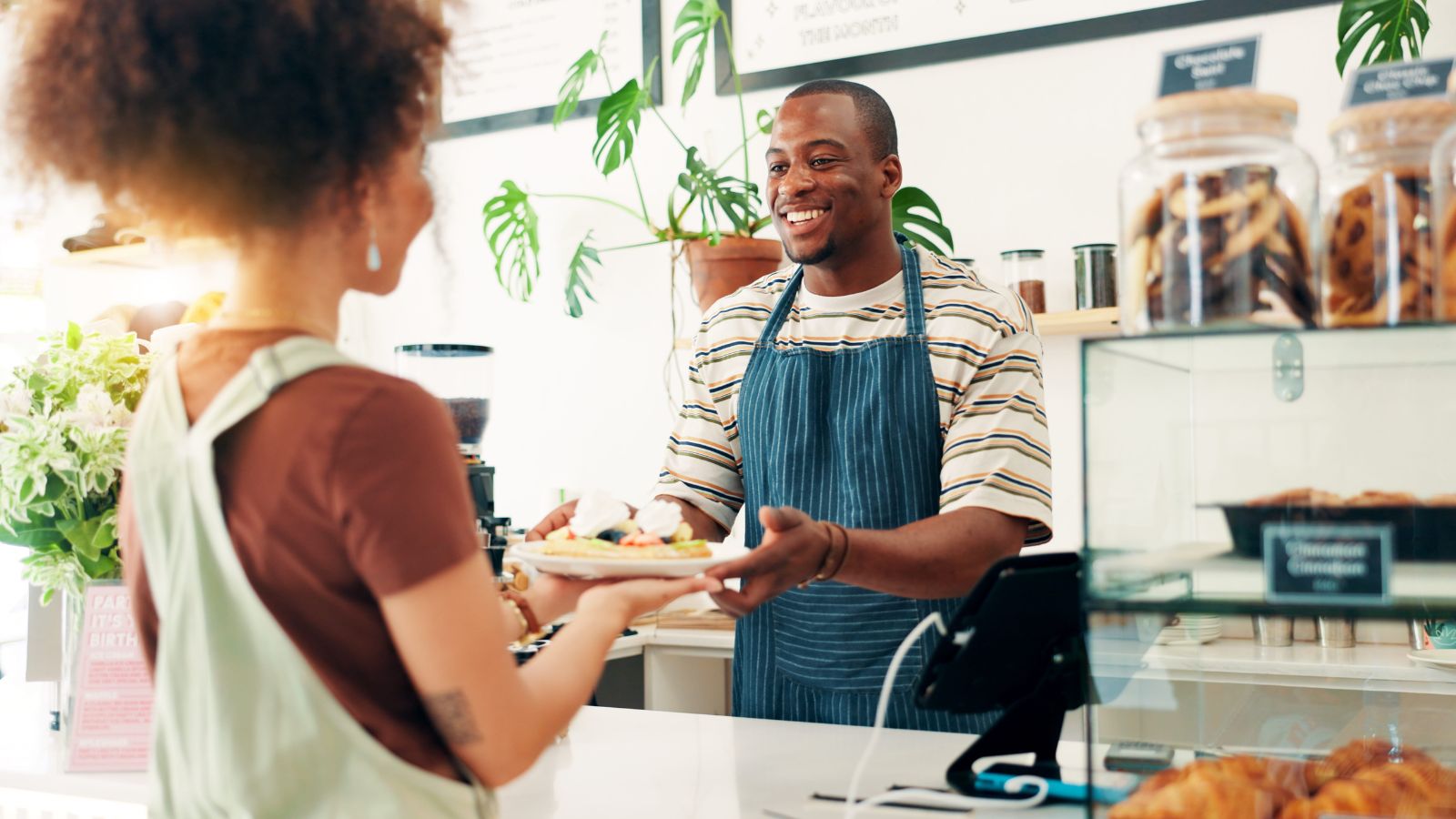 A photo of a traveler entering a small European bakery and greeting the shopkeeper, friendly interaction.