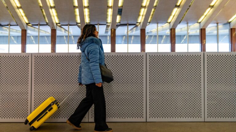 A photo of a woman carrying luggage in a transit station.