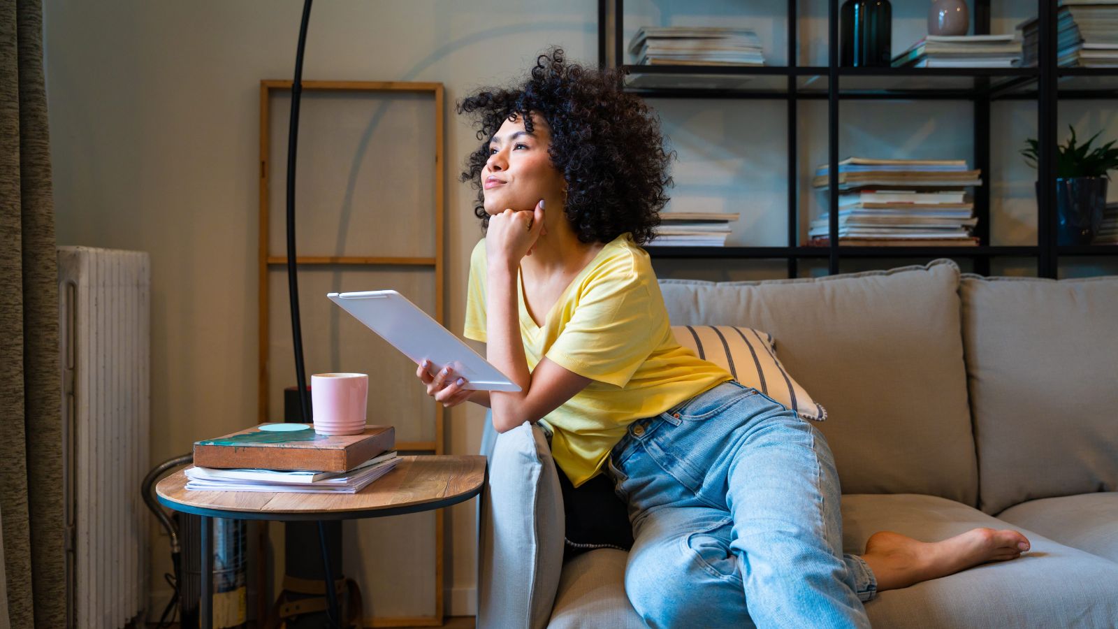 A photo of a traveler at home planning trip on laptop smiling idealistic imagining perfect vacation maps and notes.
