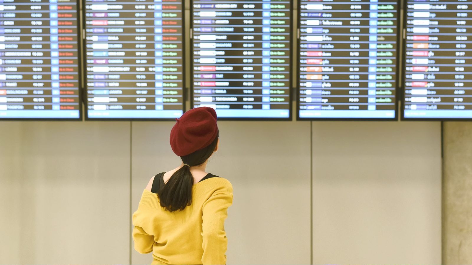 A photo of a traveler looking at phone with multiple bookings and schedule looking slightly overwhelmed planning travel day.
