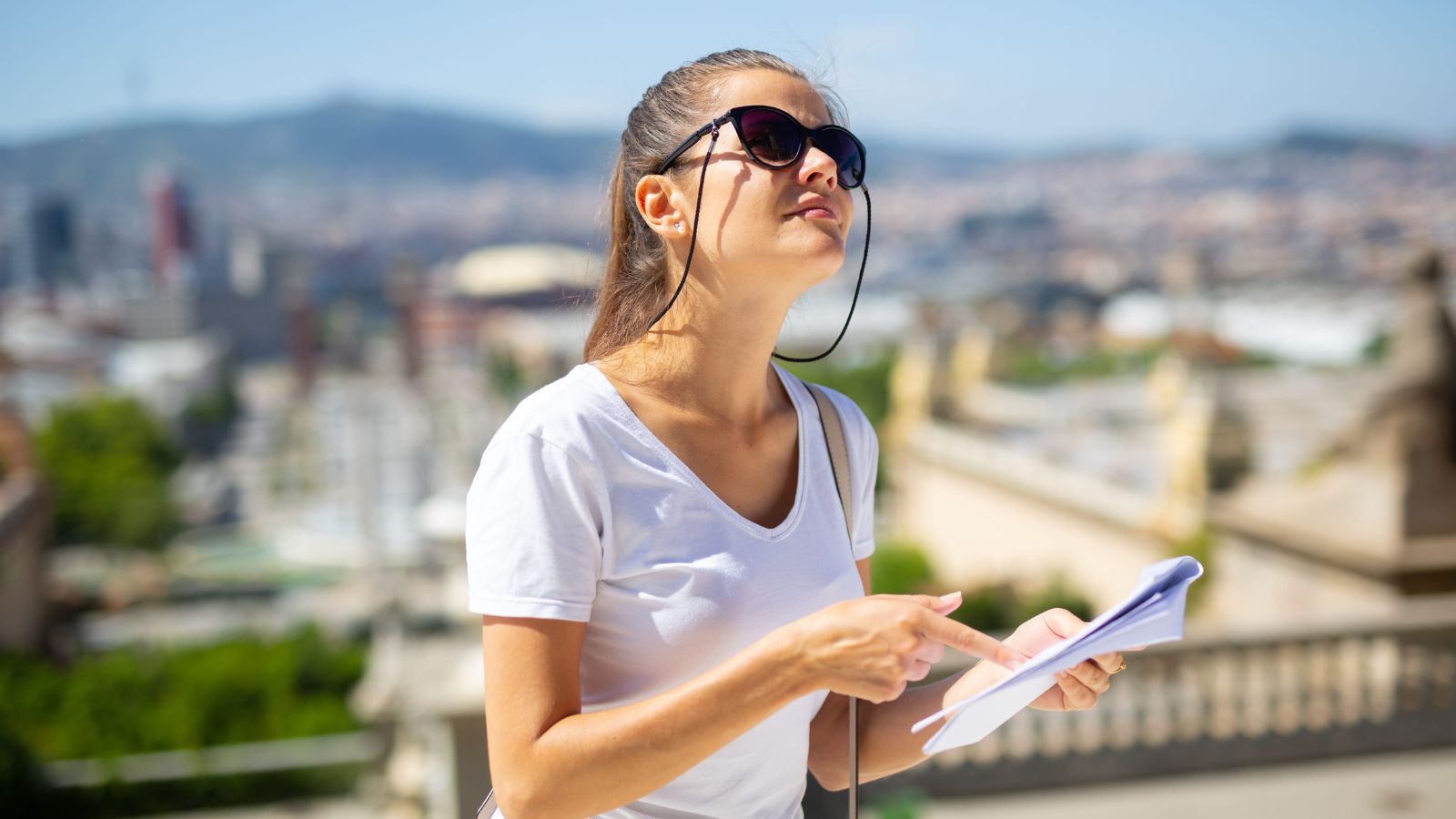 A photo of a woman looking around, holding an itinerary.