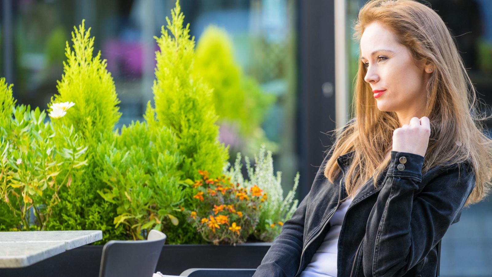 A photo of a solo traveler sitting peacefully at quiet café or park bench enjoying calm moment thoughtful relaxed travel slow pace natural light candid.