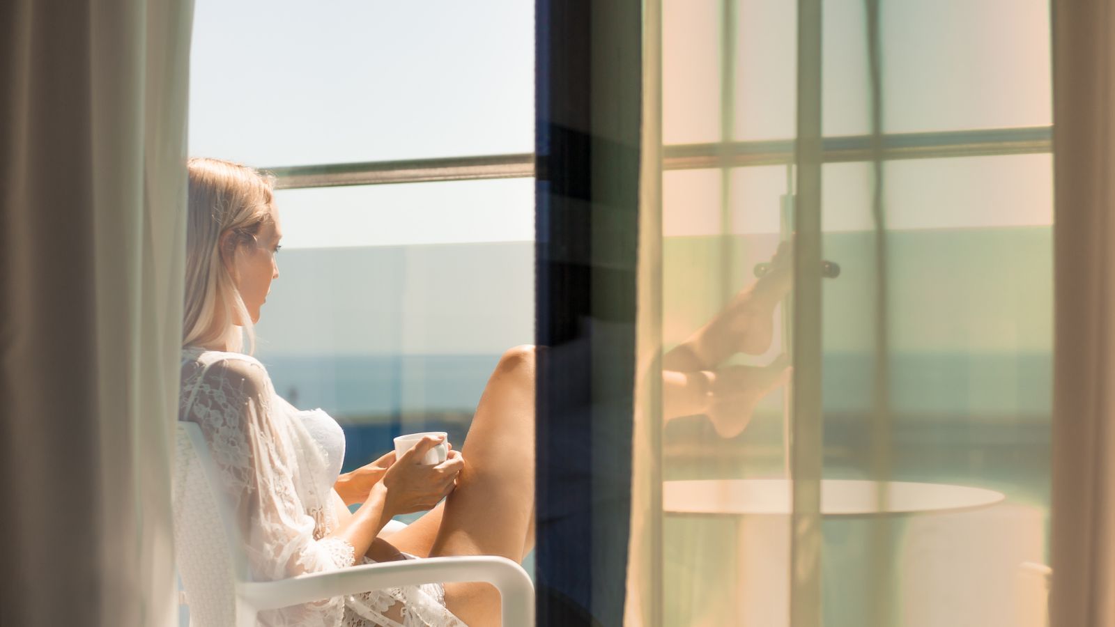 A photo of a woman enjoying the view of ocean from the balcony.