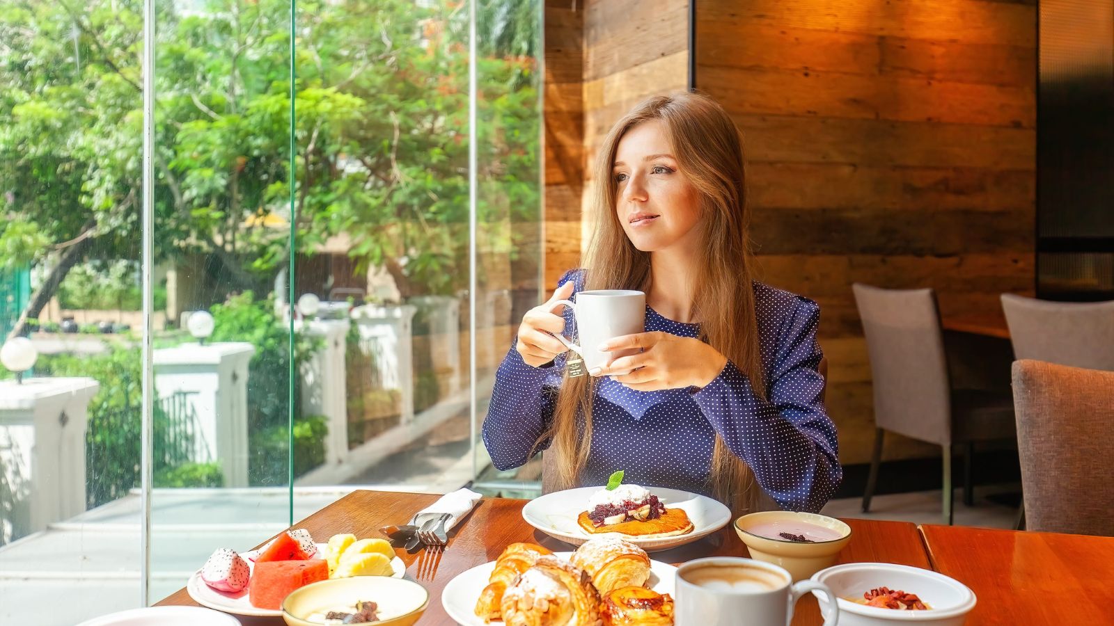 A photo of a traveler relaxing at cafe or hotel room settling in slow first day vacation peaceful no rush natural light.
