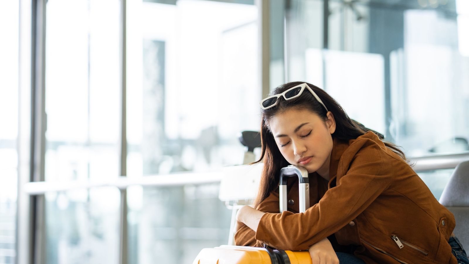 A photo of a traveler with luggage moving through airport or train station looking tired fatigued frequent travel transitions.
