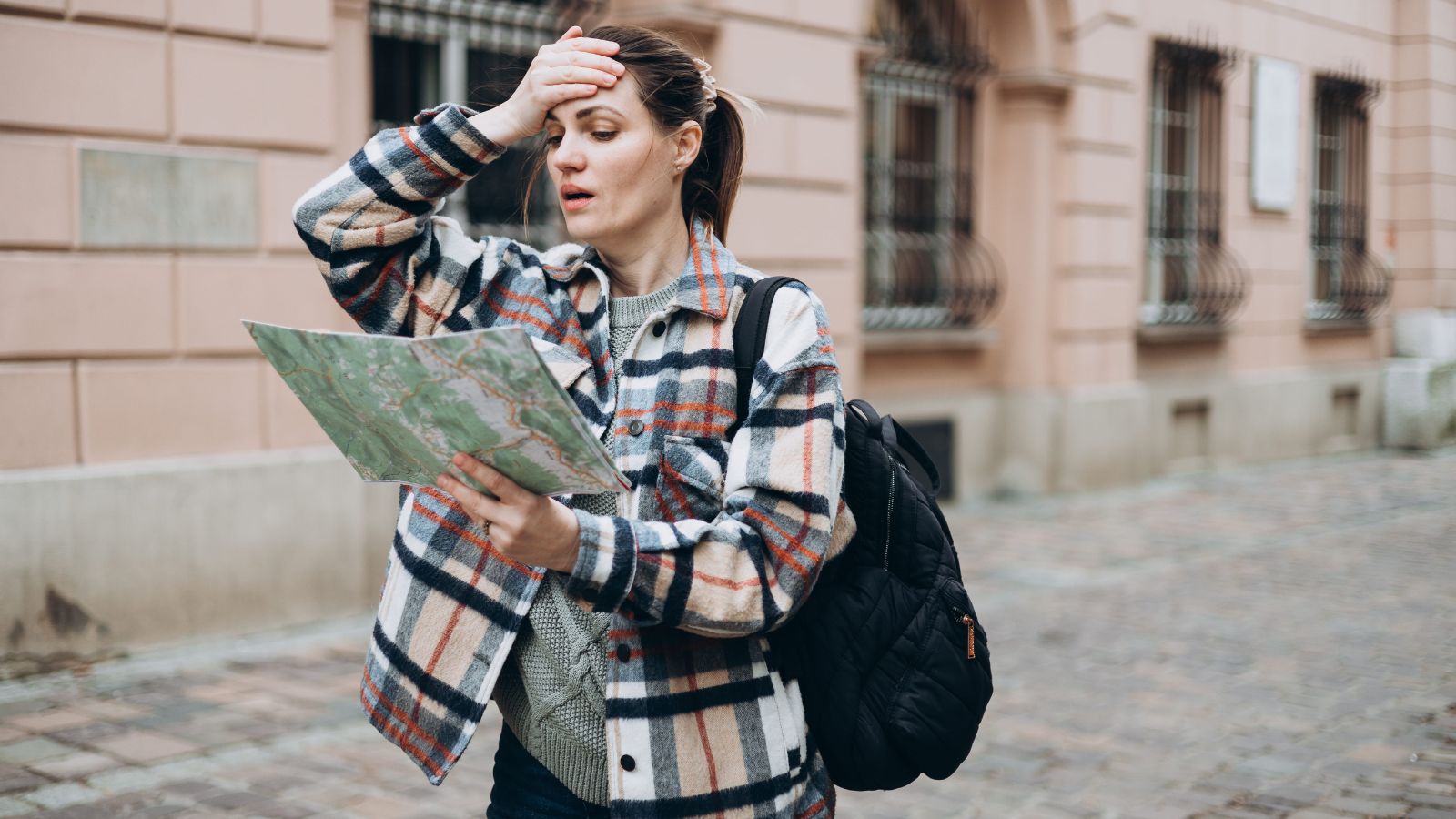 A photo of a traveler walking quickly through tourist area checking phone itinerary looking tired.