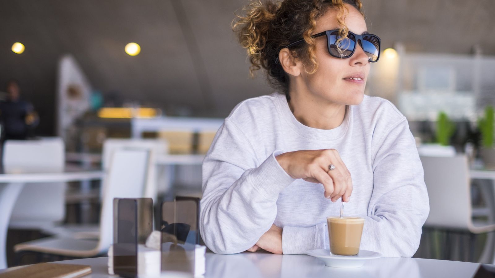 A photo of traveler sitting at café terrace alone enjoying view thoughtful relaxed unhurried atmosphere morning light candid.