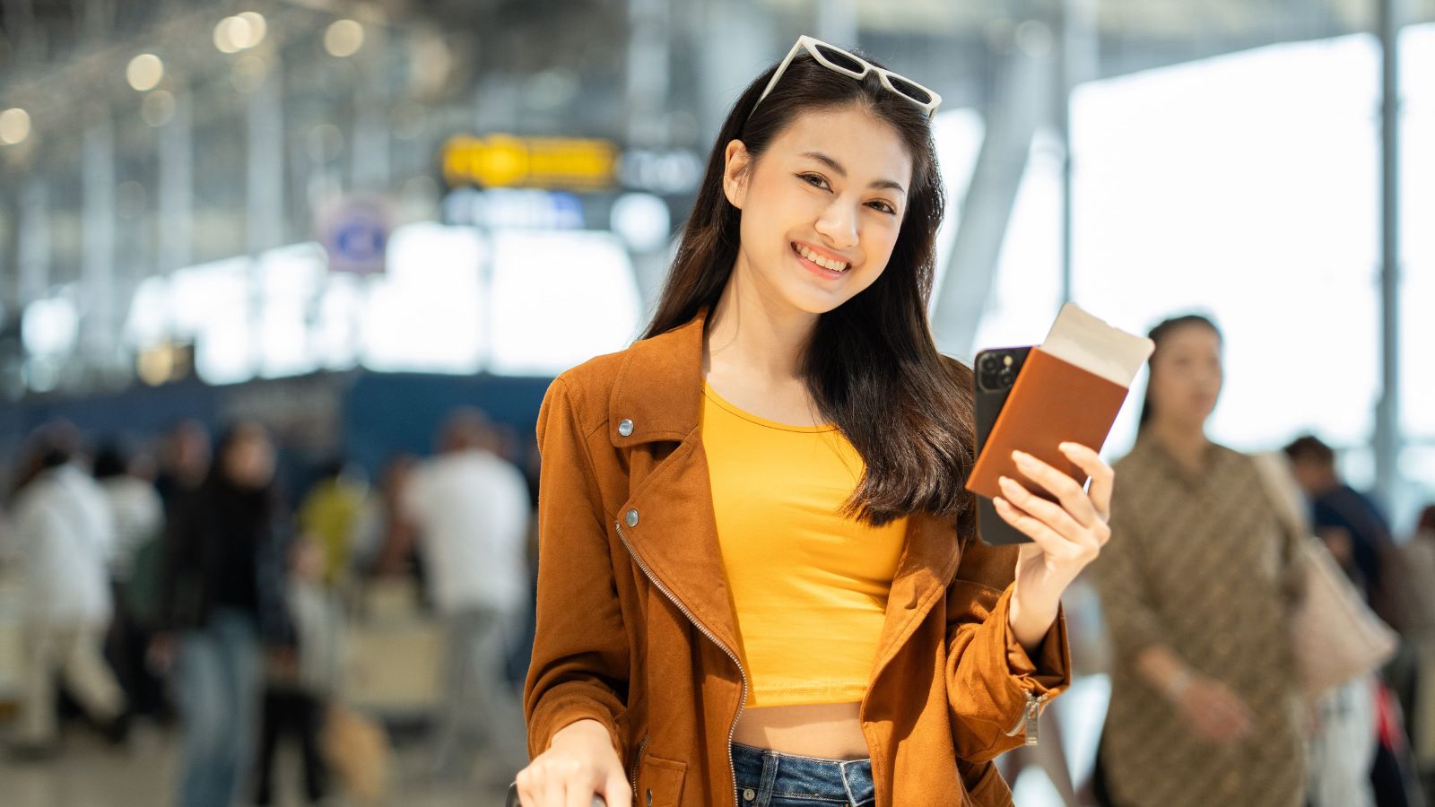 A photo of a happy traveler holding a boarding pass at the airport after finding an affordable flight deal.